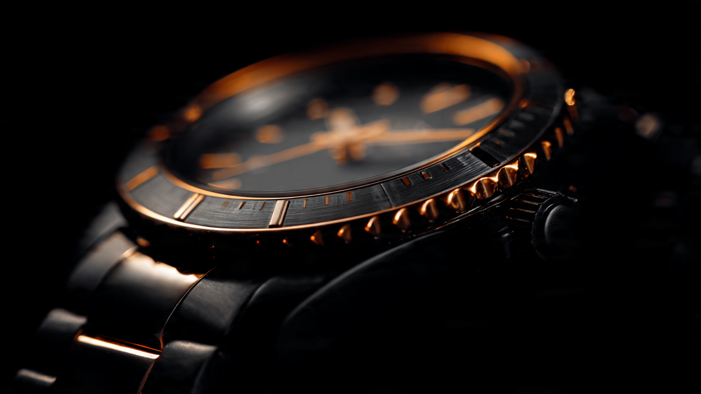 Macro photograph of a black ceramic watch with integrated bracelet under warm amber directional lighting showing polished and satin-finished zirconium oxide surfaces