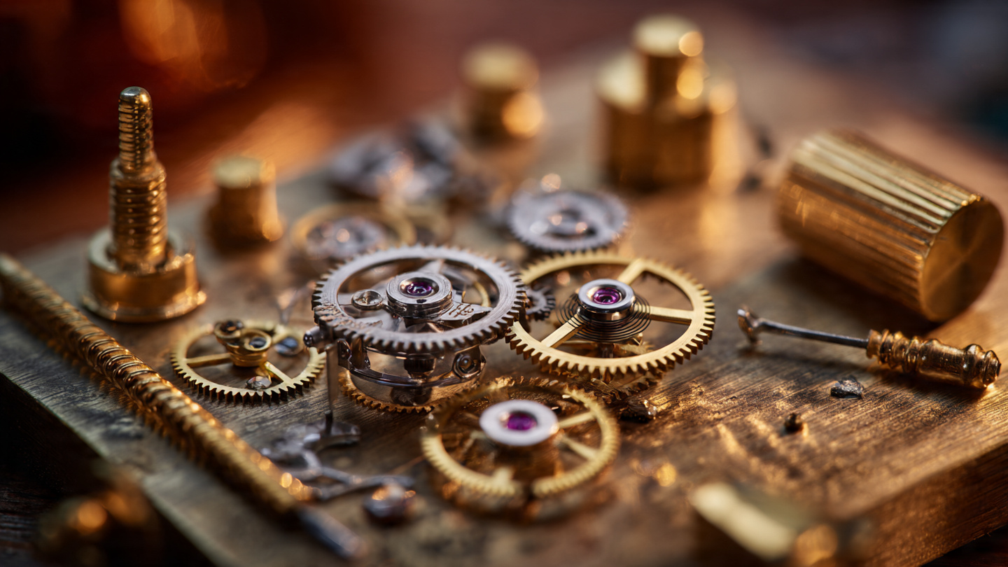 Swiss watch movement components arranged on a watchmaker's bench under warm golden light
